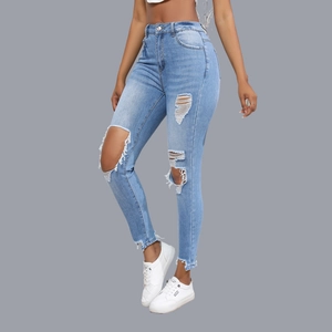 Detail of light blue skinny jeans featuring distressed knee rips and frayed hem design