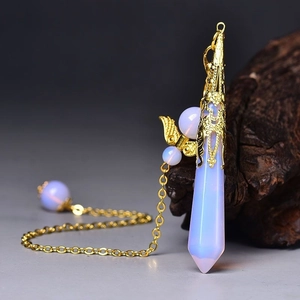 Macro shot of hexagonal opalite crystal pendant with golden angel wings and chain