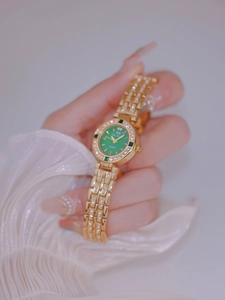 Close-up of gold ladies watch with green dial and sparkling rhinestones on band