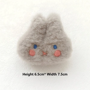 Macro view of grey plush bunny pin with embroidered face and 6.5cm height dimension