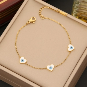 Detail of gold heart charms with evil eye enamel on a beige jewelry display box