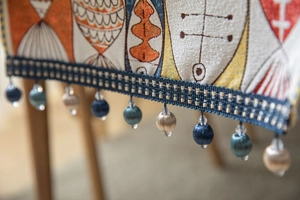 Detailed close-up of chenille table runner with fish patterns and blue tassel beads