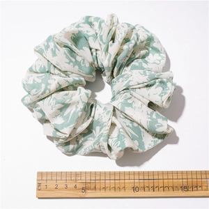 Oversized green and white floral fabric scrunchie with 14cm diameter on white background