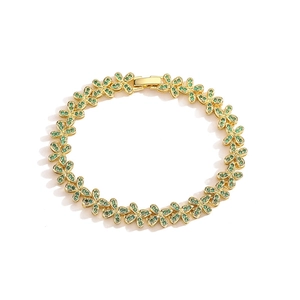 Detailed view of a gold flower bracelet featuring vibrant green cubic zirconia accents