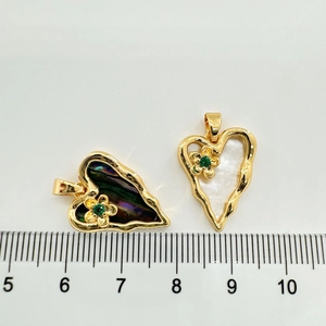 Detailed macro view of heart pendants with natural shell inlay and gold floral accents