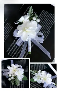 Close-up of white silk wedding boutonniere with pearls, green leaves and organza ribbon