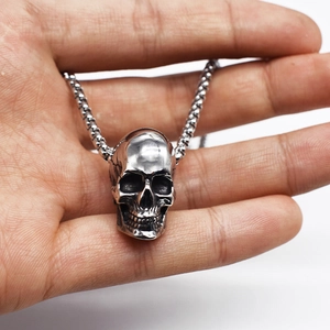 Macro shot of silver hip hop skull pendant being held in palm to show metallic details