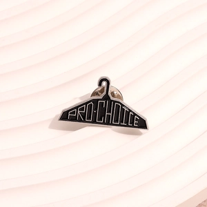 Creative black hanger enamel pin with white PRO-CHOICE text on wavy background
