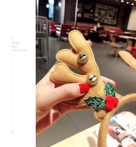 Close-up of brown plush reindeer antlers headband with gold bells and holly leaves