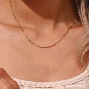 Primo piano di una collana a catena a corda in acciaio placcato oro 18K su un modello