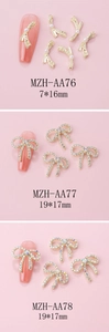 Detailed views of gold alloy bow nail charms with pearls and rhinestones on pink nails