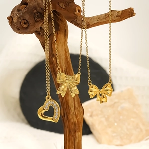 Trois colliers en acier inoxydable plaqué or 18 carats avec pendentifs nœud et cœur