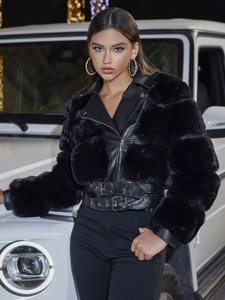 Detail of black faux fur and leather biker jacket with metallic buckles and waist belt