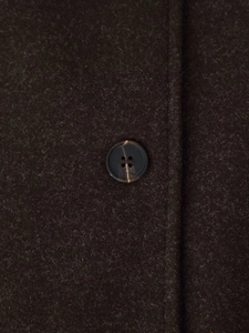 Detailed macro view of dark brown wool fabric texture and resin button on winter coat