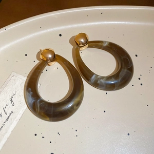 Macro shot of resin drop earrings with tortoiseshell pattern on a ceramic tray