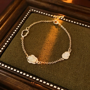 Detail of golden hulu bracelet with zircon inlay and white jade on green velvet