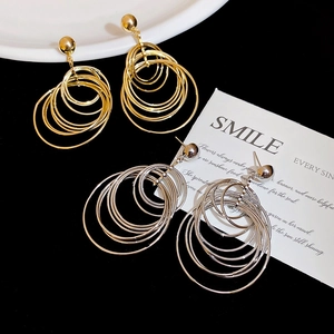 Detail of multi-layer metallic hoop earrings in gold and silver finish on a black surface