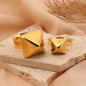 Macro di anelli a piramide in acciaio al titanio placcato oro 18k su pietra beige