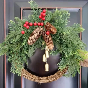 Christmas wreath with green cypress branches, pine cones and gold bells on dark wood door