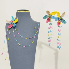 Dettaglio della collana di perline floreali fatta a mano e orecchini con nappine colorate