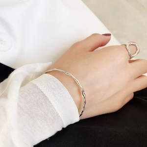 Irregular wave pattern silver bangle and ring set shown on model with minimalist outfit
