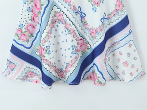 Détail de l'imprimé rose et nœud bleu sur une mini robe en satin blanc à fleurs
