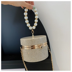 Detail of champagne gold evening clutch featuring a pearl handle and sparkling rhinestones