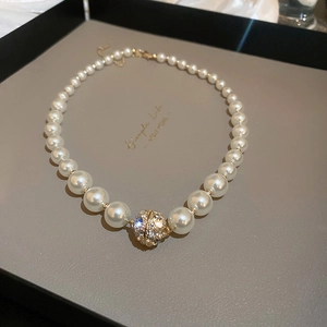 Detailaufnahme einer Vintage-Perlenkette mit Kristallkugel in einer Geschenkbox