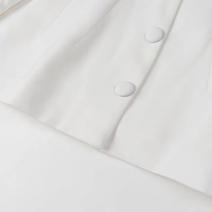Detail of white textured fabric with fabric-covered buttons on an elegant women's suit