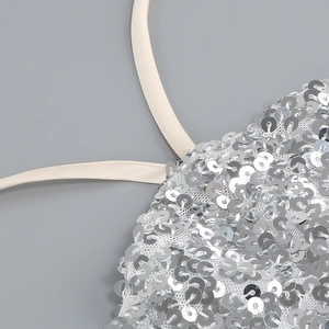Detail of silver sequins on white mesh with elegant cream satin shoulder straps