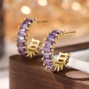 Macro shot of 925 silver earrings with purple square-cut zircons in gold settings