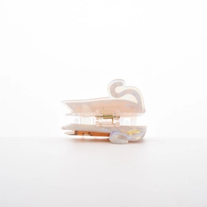 Detailed view of swan hair claw made of pearlescent orange and white acetate material