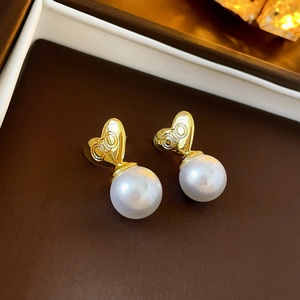 Detailed view of heart-shaped pearl earrings with gold metallic finish and white pearls