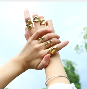 Close-up of 18K gold plated lava style stainless steel rings on hands with sky backdrop