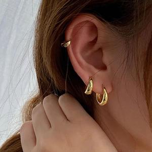 Close-up of elegant gold hoop earrings in three sizes worn by a model