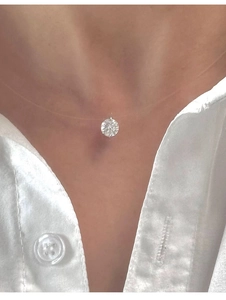 Detail of a sparkling moissanite pendant on a transparent fishing line necklace