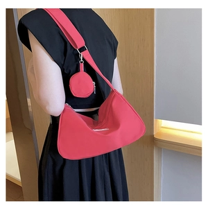 Side view of red nylon hobo bag with wide shoulder strap and round coin purse accessory