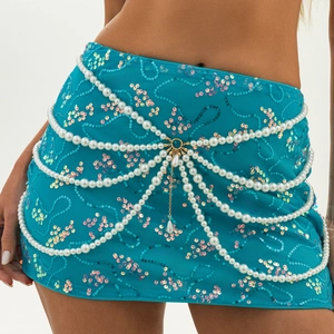 Close-up of multi-layer faux pearl waist chain on a sequined blue mini skirt detail