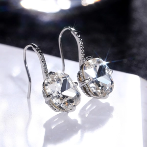 Macro shot of silver drop earrings featuring radiant cushion-cut zircon and pavé hook