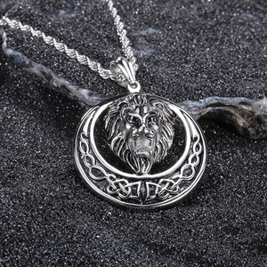 Detailed view of silver lion head pendant with Celtic knots on textured black stone