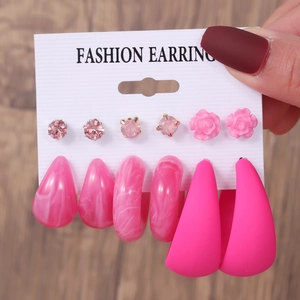 Detailed view of six pairs of pink heart-themed earrings and studs on a display card