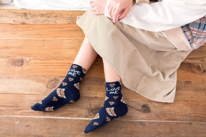 Close-up of navy blue cotton socks with cartoon fox and heart patterns on wood floor