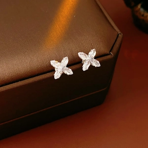 Détail des boucles d'oreilles fleur en zircon argenté sur une boîte à bijoux brune