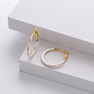 Detailed view of two-tone gold and white enamel hoop earrings on geometric stands