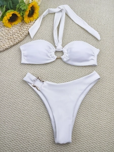 Detailed flat lay of a white bikini set featuring gold buckle accents and a summer beach aesthetic