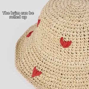 Detail of beige straw hat with red heart crochet patterns and flexible foldable brim