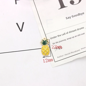 Detail view of yellow and green pineapple enamel charm with 23mm x 12mm size markings