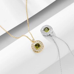 Macro shot of gold and silver necklaces with square olive green gemstone pendants