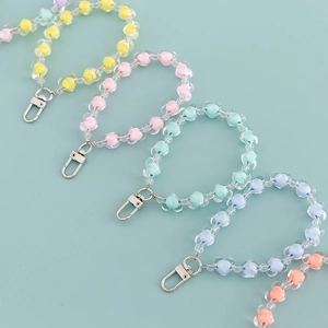 Colorful acrylic flower bead keychains with silver lobster clasps on green background