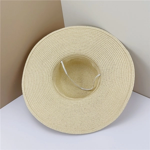 Vue détaillée d'un chapeau de paille beige montrant l'intérieur et le cordon élastique